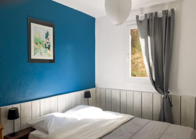 Chambre double avec un bardage bois sur 1 m de haut dans les tons bleu et gris.