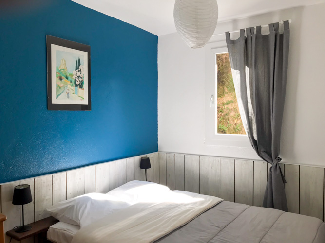 Chambre double avec un bardage bois sur 1 m de haut dans les tons bleu et gris.
