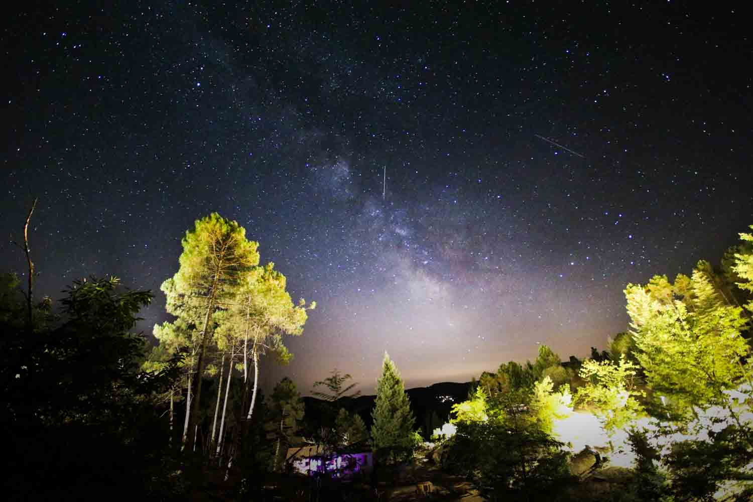 Voie lactée au dessus du village de gîtes de Ravel avec les arbres éclairés