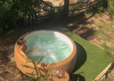 Jeune femme se détend dans un jacuzzi en pleine nature cévenole au village de gîtes de Ravel