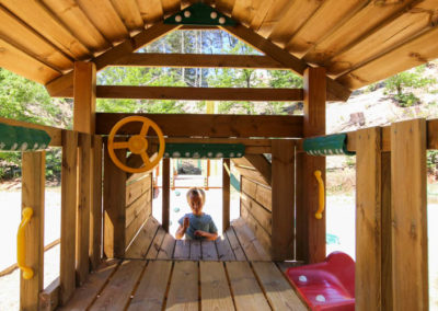Intérieur de la structure en bois de l'aire de jeux en forme de locomotive. Un enfant rentre par le devant pour ramper à l'intérieur
