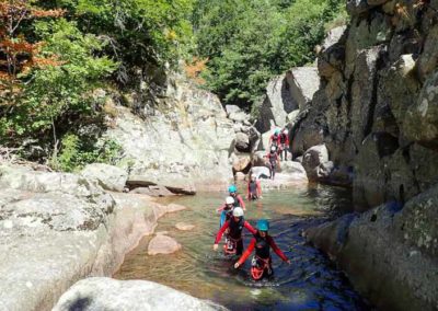 Canyonneurs marche dans l'eau entourés par les rochers de granits