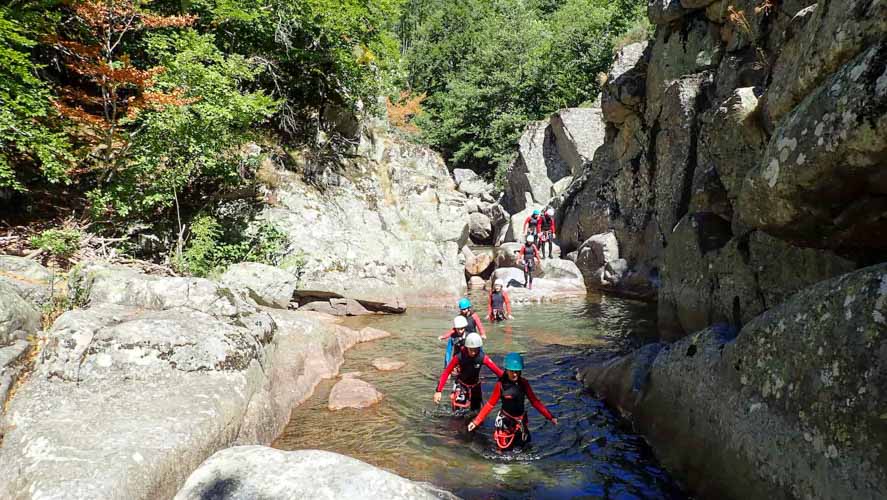 Canyonneurs marche dans l'eau entourés par les rochers de granits