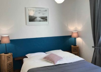 Chambre avec un lit double en 140cm décoré dans les tons bleus et gris
