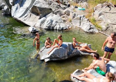 Familles avec enfants se prélassent sur les rochers de granit au milieu de la rivière en cévennes