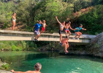 Enfants et adolescents sautent d'un petit pont dans la rivière bleu turquoise