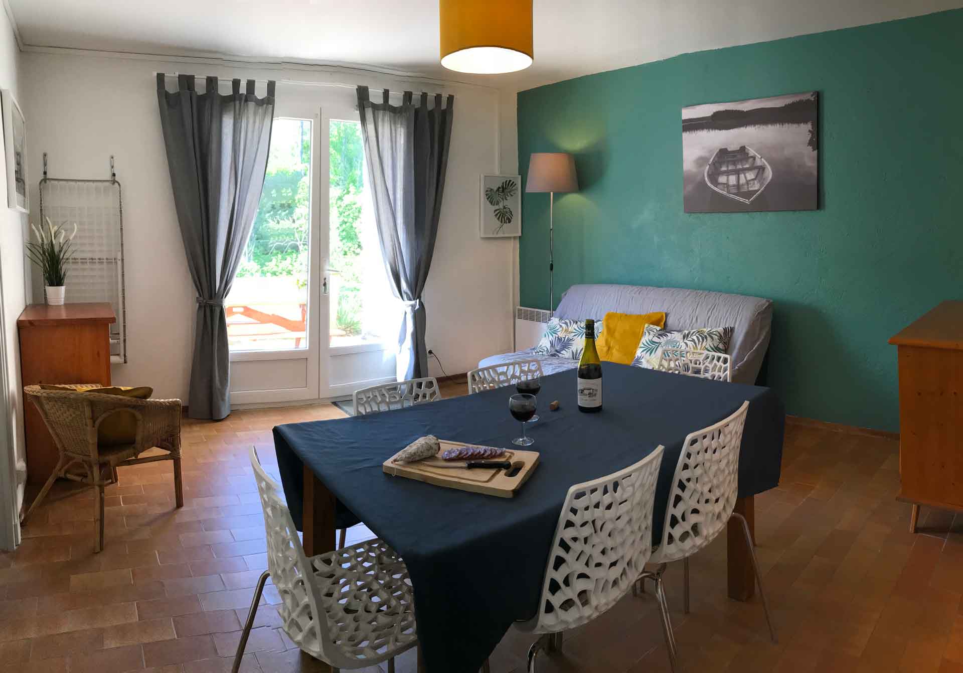 Salon salle à manger avec de jolis couleurs verte et moutarde, la double porte vitrée donne directement sur la terrasse ensoleillée