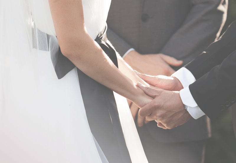 Echange de consentements lors d'une cérémonie de mariage avec un gros plan sur les mains des mariés