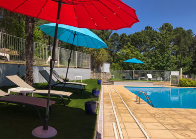 Transats et les parasols au bord de la piscine rectangle du village de gîtes de Ravel en Cévennes