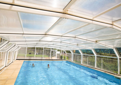 Enfants se baignent dans la piscine avec l'abri télescopique de la piscine en place