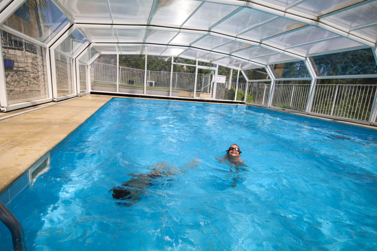 Enfants se baignent dans la piscine sous l'abri télescopique en avril