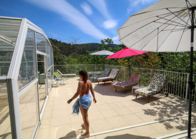 Abri télescopique de la piscine en place. journée ensoleillée, les parasols sont de sortis