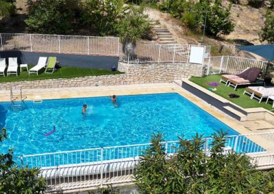 piscine rectangle bleu de 10m par 7m avec une grande plage bordée par la nature