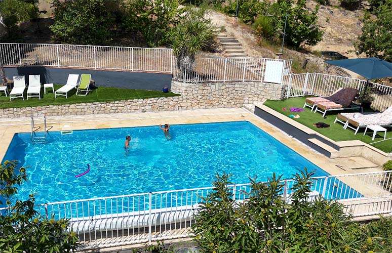 piscine rectangle bleu de 10m par 7m avec une grande plage bordée par la nature