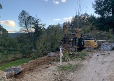 Pelle mécanique réalisant un enrochement pour déplacer la route d'entrée du village de gîtes