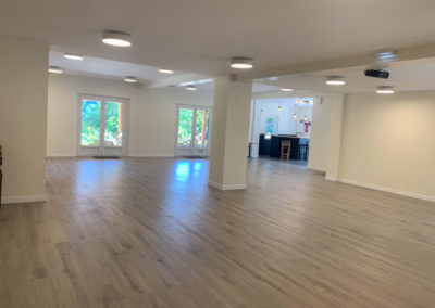 Salle de réception de jour avec les luminaires en fonction. Salle vide avec parquet gris clair.