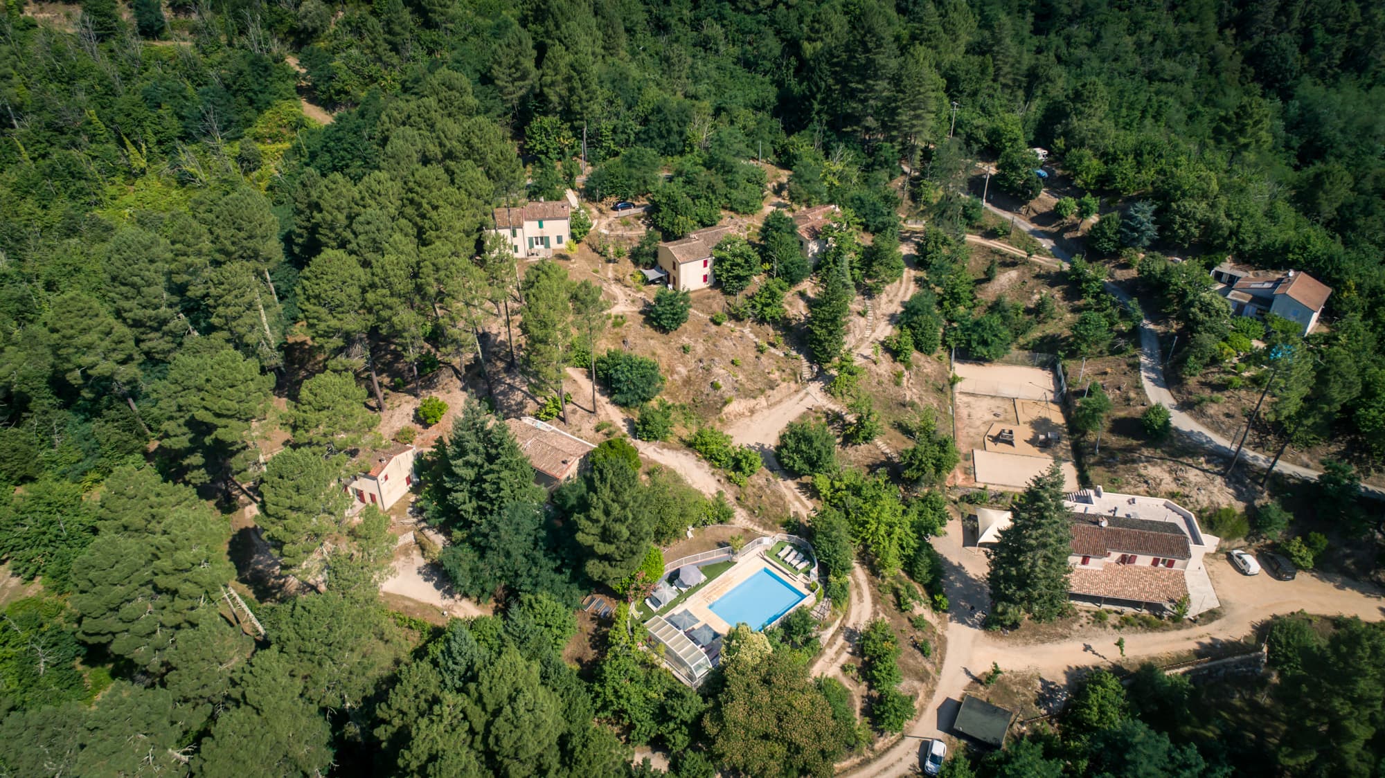 Le domaine vu du ciel, avec la piscine, le bâtiment d'accueil, les aires de jeux, les maisonnettes entouré de verdure